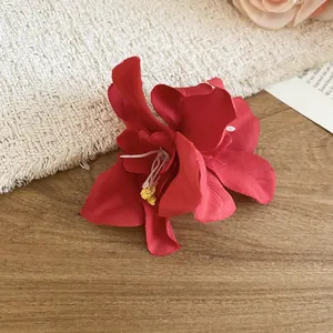 Macro view showing the realistic fabric petals of this elegant red floral hair clip