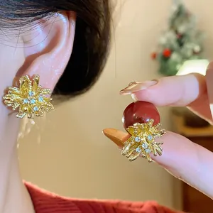 Close-up of festive red pearl earrings with sparkling firework-shaped gold settings.