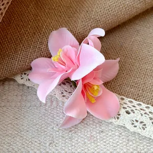 Close-up detail of a pink fabric artificial flower hair clip with rustic burlap background