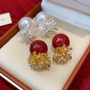 Detail view of firework pearl stud earrings with red and white pearls in a gift box.
