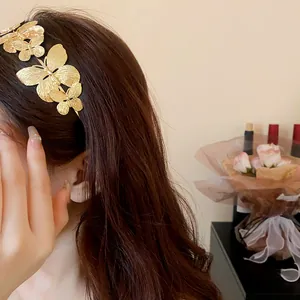 Primo piano di un elegante cerchietto in metallo dorato con farfalle 3D su capelli mossi