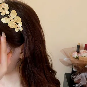 Dettaglio di cerchietto con farfalle in metallo dorato, elegante accessorio per capelli.