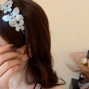 Primo piano di un cerchietto in metallo con farfalle argentate indossato da una modella.