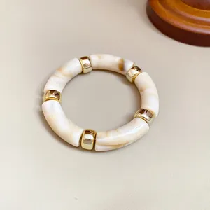 Macro detallada de una pulsera vintage de acrílico marmoleado con detalles en oro