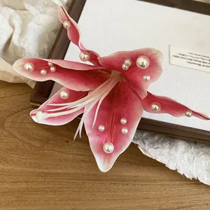 Detailed macro close-up of a pink fabric lily flower hair clip with elegant pearl beads.