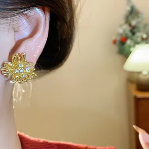 Macro detail view of elegant gold firework stud earrings with crystals worn on an ear