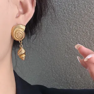 Vista detallada de pendientes de concha dorados con textura espiral intrincada