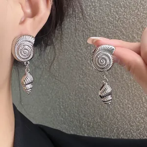Primer plano de elegantes pendientes colgantes de caracola plateados en una oreja
