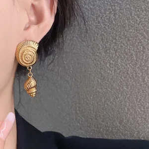 Primer plano de elegantes pendientes de concha dorados con textura detallada