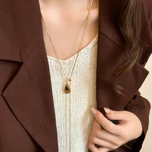 Detail of a vintage-style tiger eye stone lariat necklace worn with a brown blazer.