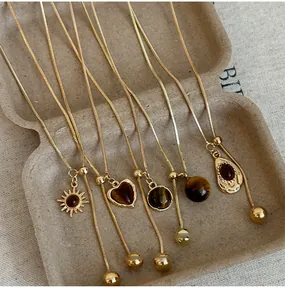 Close-up of gold-plated necklaces with tiger eye stones and adjustable sliding chains