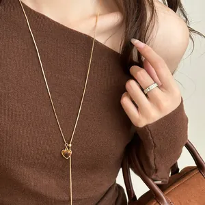 Close-up detail of a gold-plated tiger eye heart pendant necklace on a brown sweater