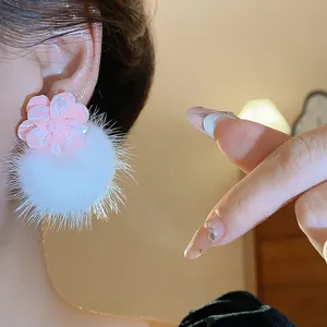 Primo piano dettagliato di orecchini a fiore in resina rosa con pompon di pelliccia bianca