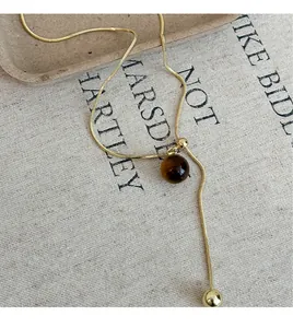 Close-up of gold-plated tiger's eye adjustable necklace on linen background