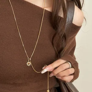 Detailed view of a gold-plated tiger's eye sunburst pendant necklace on brown sweater