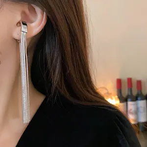 Close-up shot of a minimalist silver metal tassel ear cuff worn on the model's ear