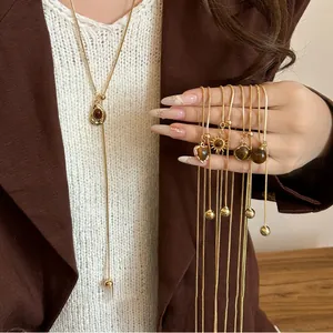 Detail view of adjustable gold plated tiger eye stone necklaces with heart and sun pendants.