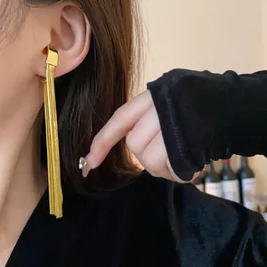 Detailed close-up showing a stylish golden metallic tassel ear cuff on a model's ear