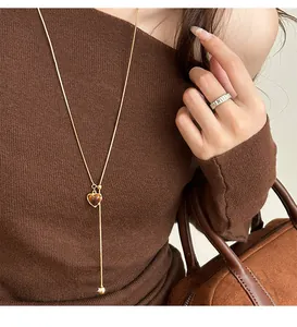 Macro view of gold Y-shaped necklace with a heart tiger eye pendant on a sweater