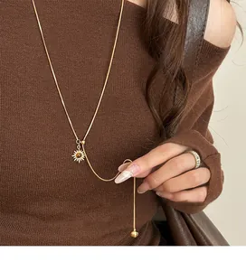 Close-up of gold-plated tiger eye sun pendant on a long adjustable sweater chain.