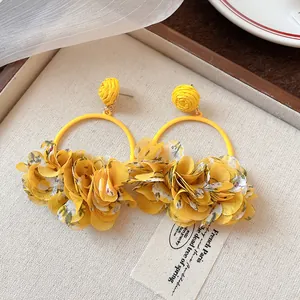 Macro detail of yellow fabric flower hoop earrings showing intricate floral petal texture