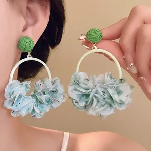 Macro view of blue floral fabric petal hoop earrings with green woven stud decoration