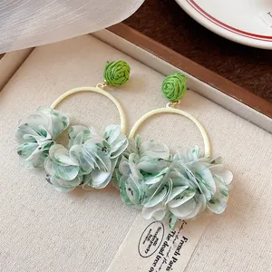 Detailed view of sweet floral fabric petal hoop earrings with a green raffia ball