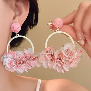 Close-up of pink fabric petal hoop earrings with rose stud detail