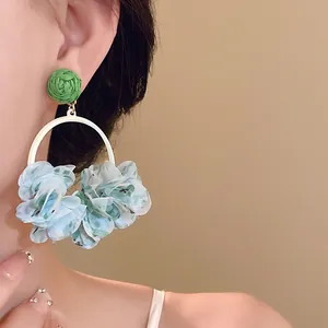 Close-up view of a model wearing sweet fabric flower petal hoop earrings in light blue.