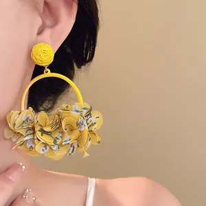 Macro detail of sweet yellow cloth petal hoop earrings featuring steel needle design