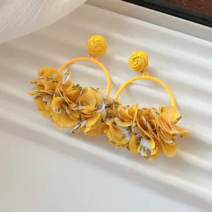 Close-up detail of stylish yellow fabric petal hoop earrings for early spring beach look