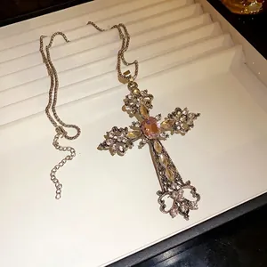 Collier avec pendentif en croix orné de strass brillants et d'une pierre rose.