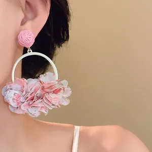 Close-up view of sweet pink floral fabric petal hoop earrings worn on model for spring style