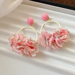 Close-up detail of sweet pink fabric floral petal hoop earrings with woven studs.