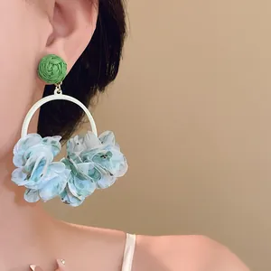 Detailed view of sweet light blue fabric petal hoop earrings worn by a model for a stylish look