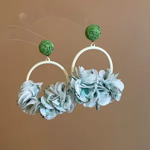 Detailed macro view of elegant green fabric flower petal hoop earrings for spring