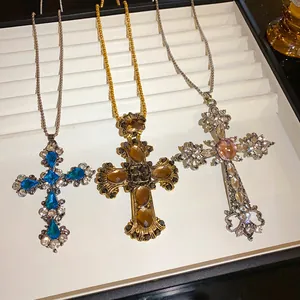 Vue détaillée de colliers avec pendentif en croix et diamants goutte d'eau en trois couleurs