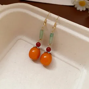 Macro detail of Chinese style resin persimmon earrings with green stone beads