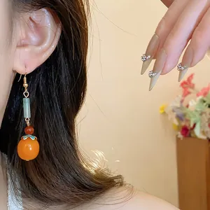 Detailed close-up view of elegant persimmon resin earrings with New Chinese style tassel design.