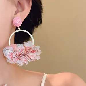 Close-up of sweet pink fabric petal round drop earrings worn by a model for a chic look