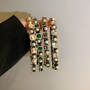 Close-up detail of stylish padded headbands featuring pearls and colorful crystal rhinestones