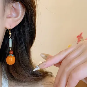 Close-up of Chinese style persimmon tassel earrings with resin and stone beads