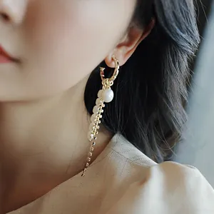 Close-up detail of geometric C-shape earring with pearl tassels and rhinestones