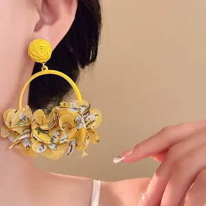 Macro detail showing vibrant yellow fabric flower petals on a stylish round hoop earring