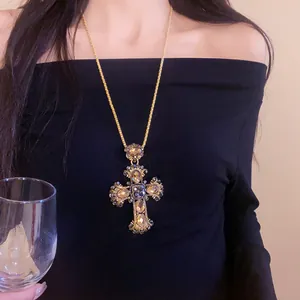 Détail du pendentif croix en strass porté sur une tenue noire