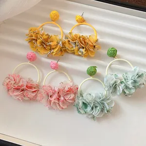 Close-up of handmade fabric petal hoop earrings in vibrant yellow, pink, and green