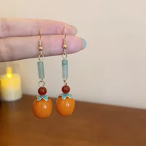 Close-up of New Chinese style persimmon drop earrings with resin beads and gold hooks