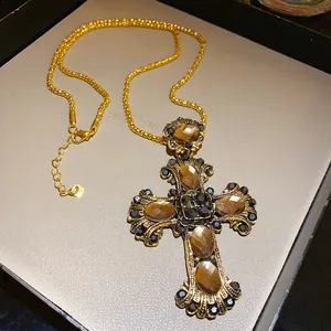 Gros plan du pendentif croix vintage doré avec pierres ambrées facettées et noires