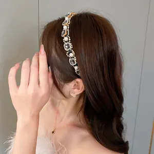 Detailed view of an elegant pearl and rhinestone headband worn on wavy brown hair
