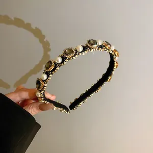 Close-up of elegant pearl and grey rhinestone headband with gold braided details